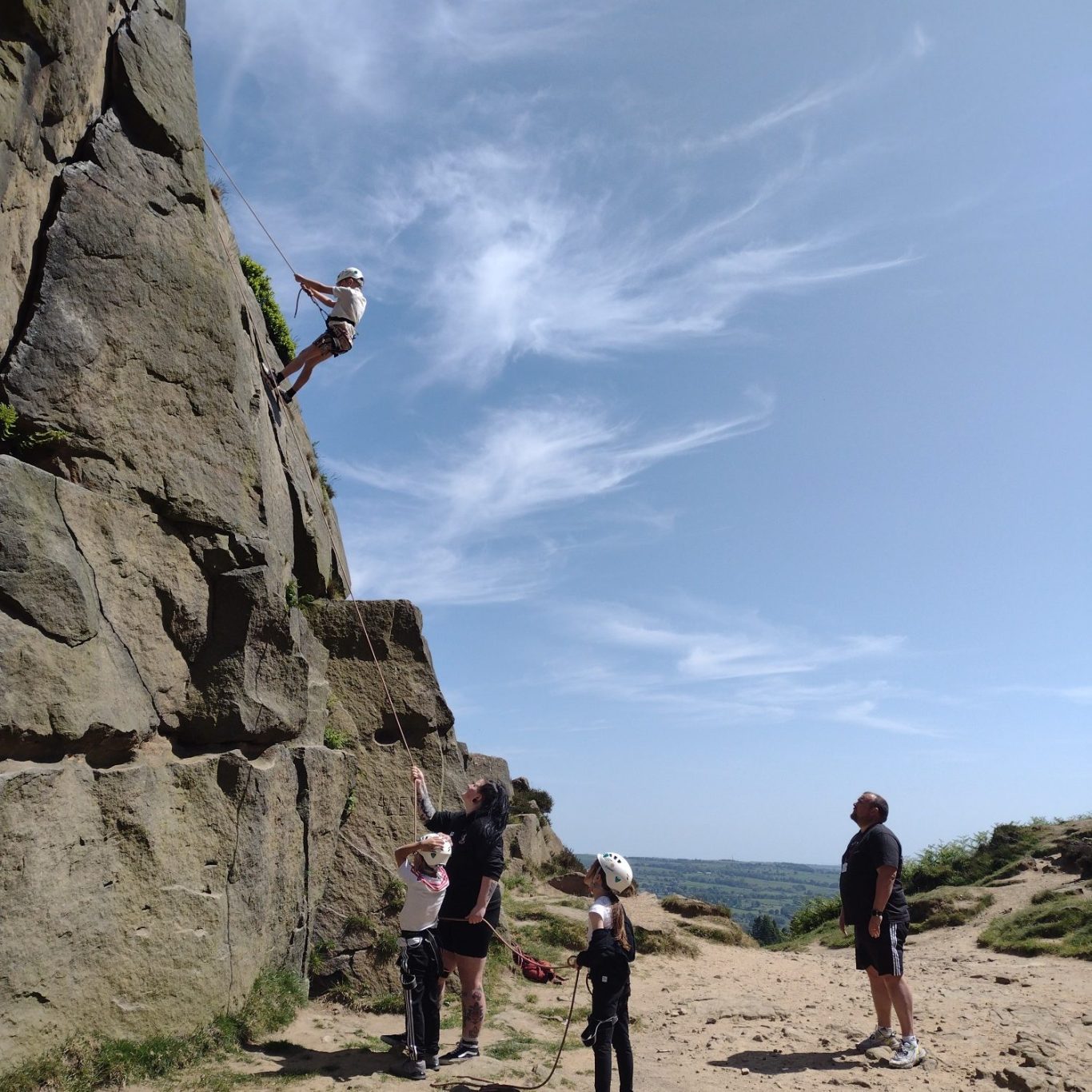 Outdoor Rock Climbing Adventures for Young People | ROAM CIC Activities A young person scaling a climbing wall with safety gear during a rock climbing session.